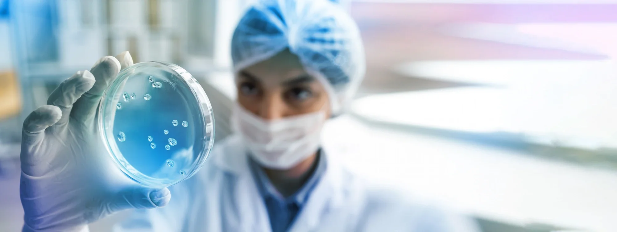 Scientist inspecting a petri dish in a cleanroom